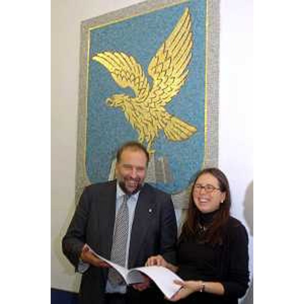 Roberto Cosolini (Assessore regionale al lavoro, formazione, università e ricerca) e Michela Del Piero (Assessore regionale alla programmazione e controllo, alle risorse economiche e finanziarie, al patrimonio e servizi generali e alle pari opportunità) con lo stemma della Regione alle spalle 