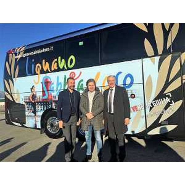 L'assessore regionale al Turismo Sergio Emidio Bini con il direttore di PromoTurismoFvg Lucio Gomiero e l'assessore di Lignano Massimo Brini davanti al nuovo pullman dell'Udinese Calcio con la gigantografia della località balneare (Foto ARC Pozzetto)