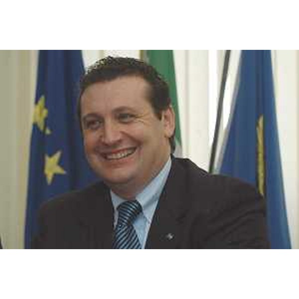 Enzo Marsilio (Assessore regionale alle risorse agricole, naturali, forestali e montagna) ritratto sorridente con le bandiere di spalle - mezzo busto 